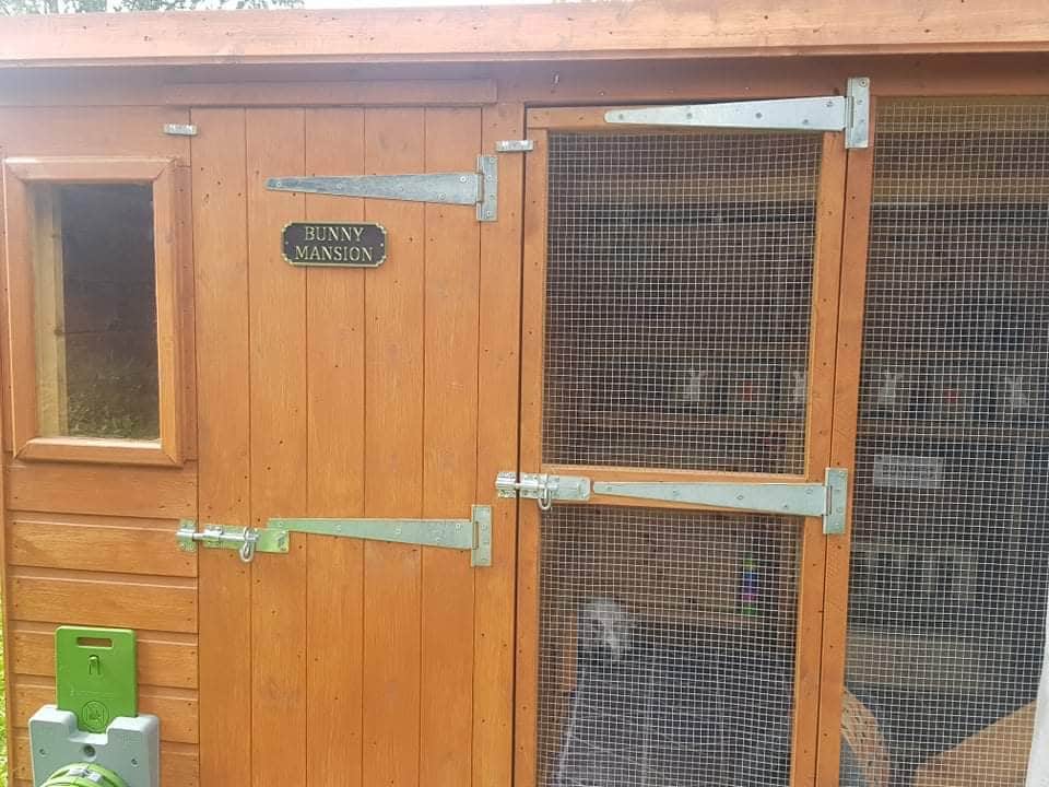 Bunny Mansion sign fitted above the door of a wooden rabbit hutch