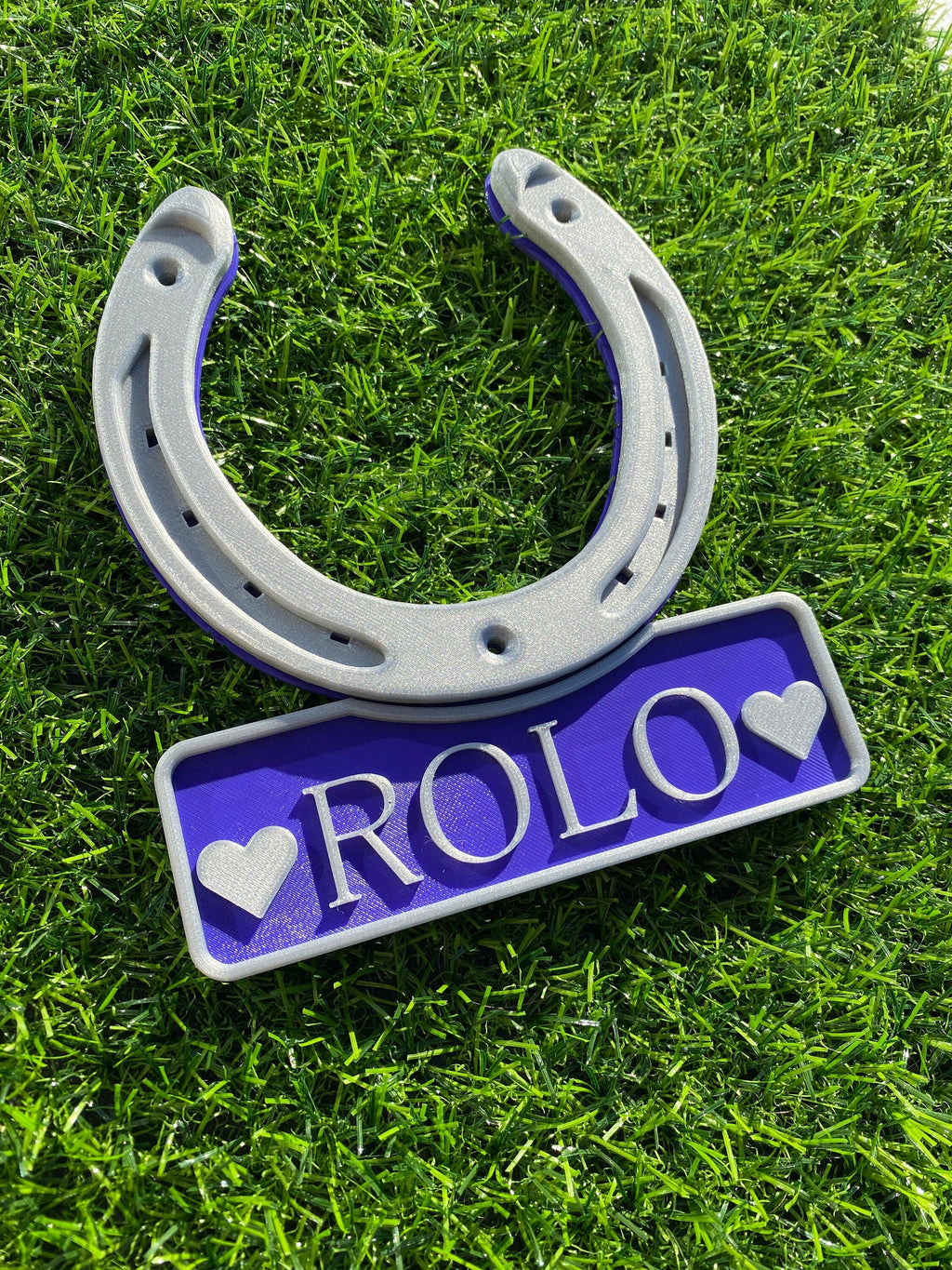 Purple horseshoe name plate with heart motifs either side of the name Rolo