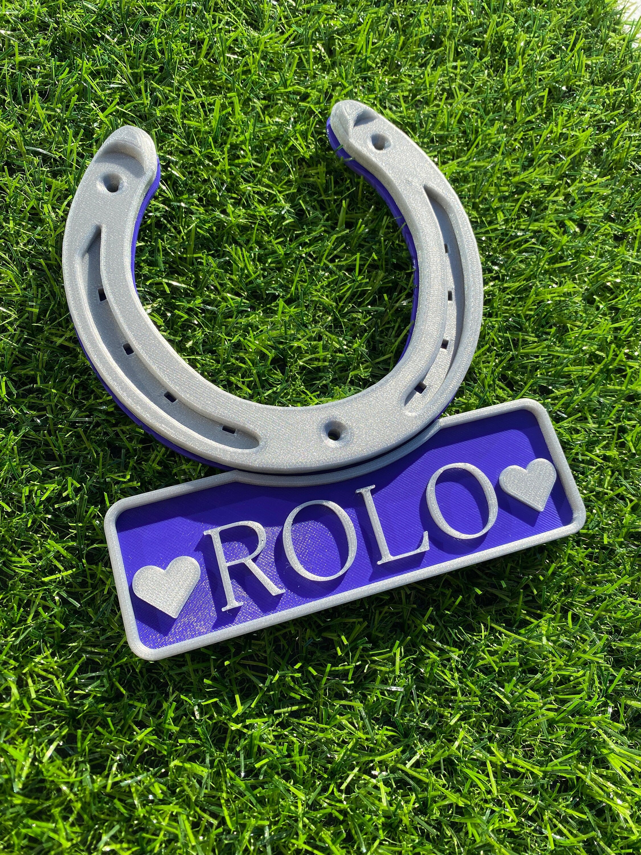 Purple horseshoe name plate with heart motifs either side of the name Rolo