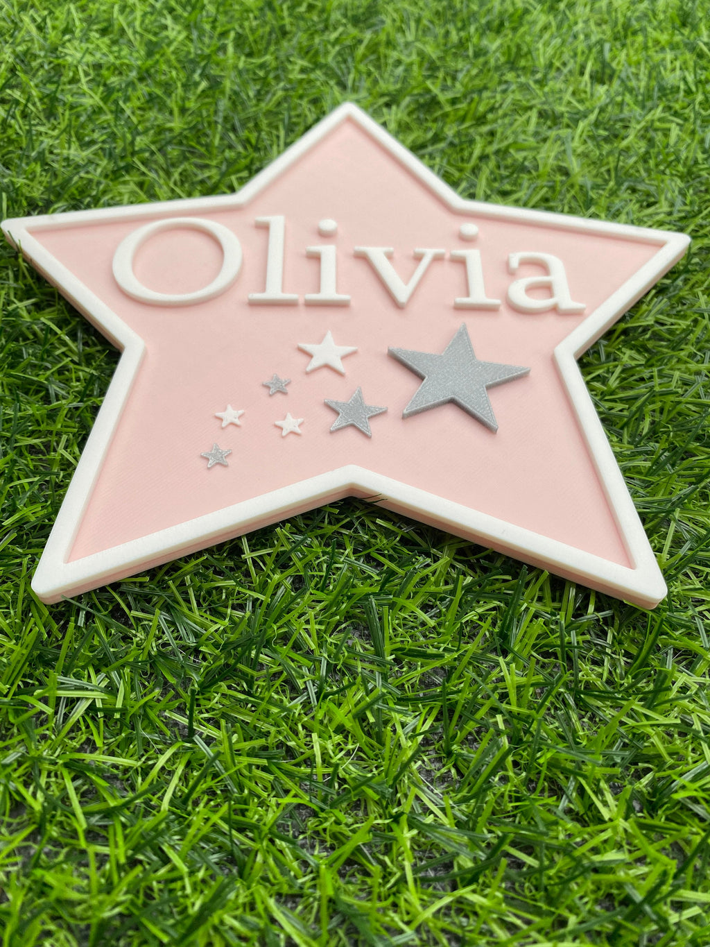 Close-up of the pastel pink Olivia star door sign with silver stars