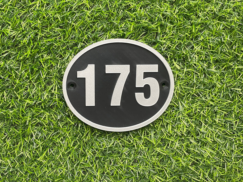 Black and silver oval house door number 175