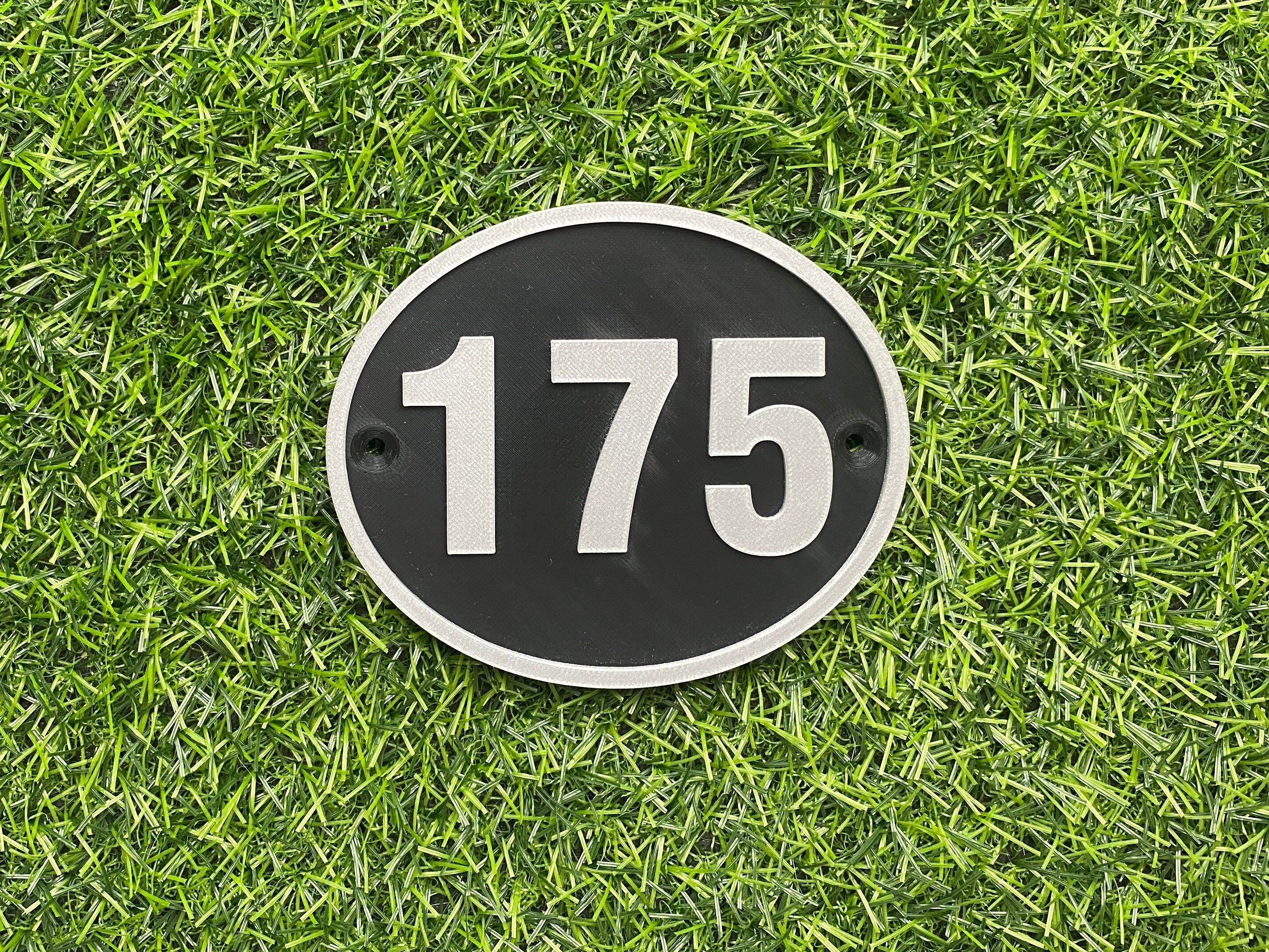 Black and silver oval house door number 175