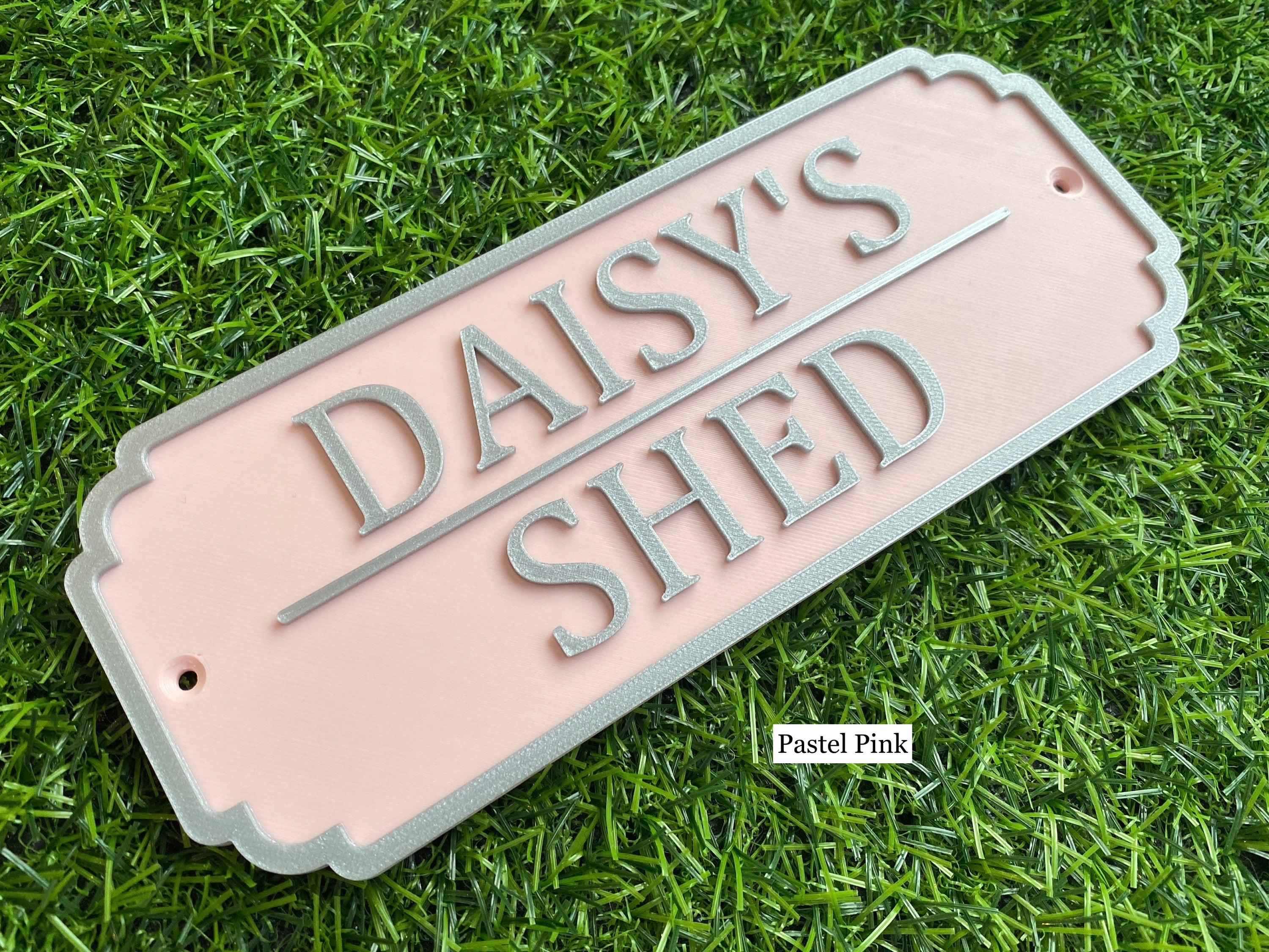 Pastel pink rabbit hutch sign with silver lettering reading Daisy's Shed