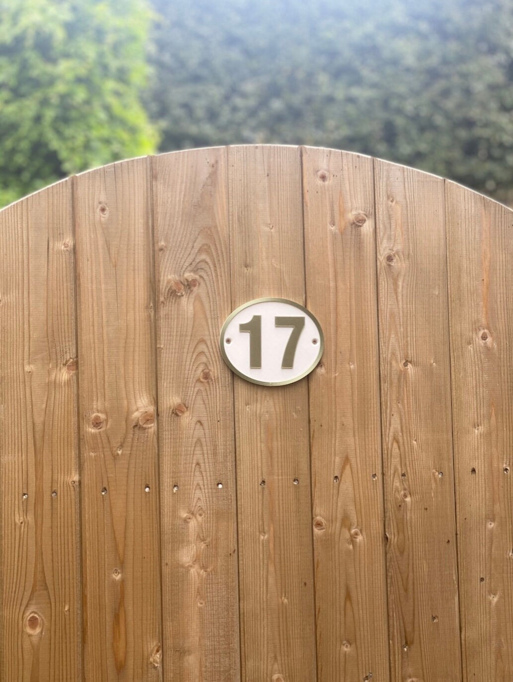 Oval house door number 17 fitted to a wooden garden gate