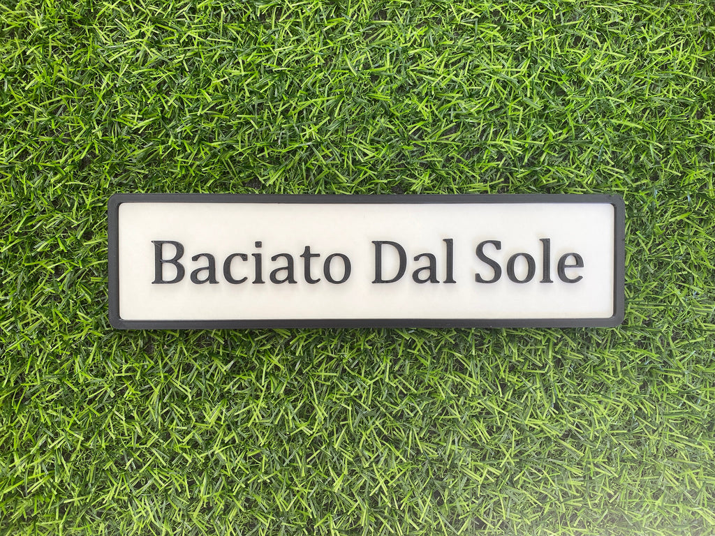 White and black contemporary door sign reading Baciato Dal Sole