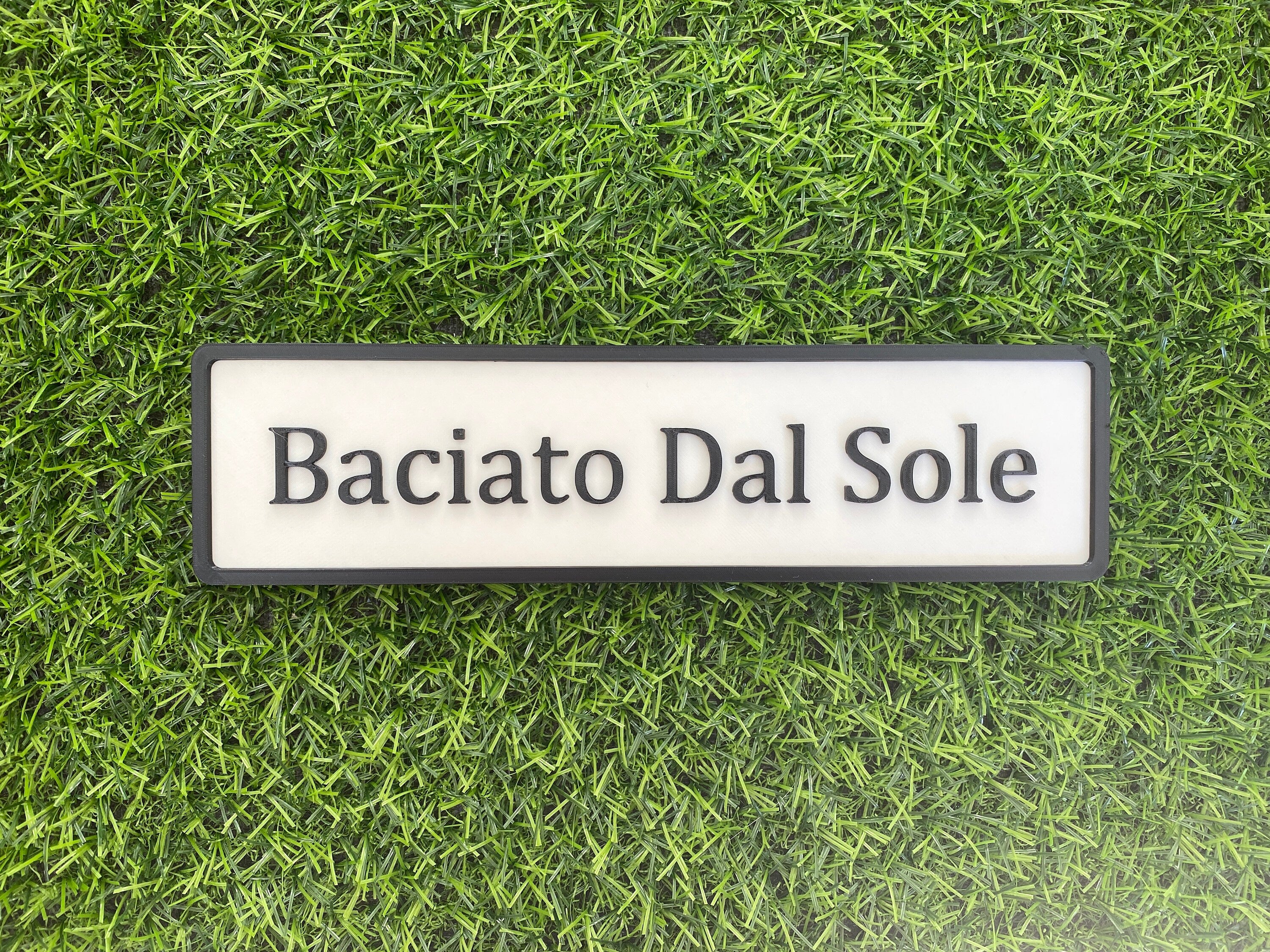 White and black contemporary door sign reading Baciato Dal Sole