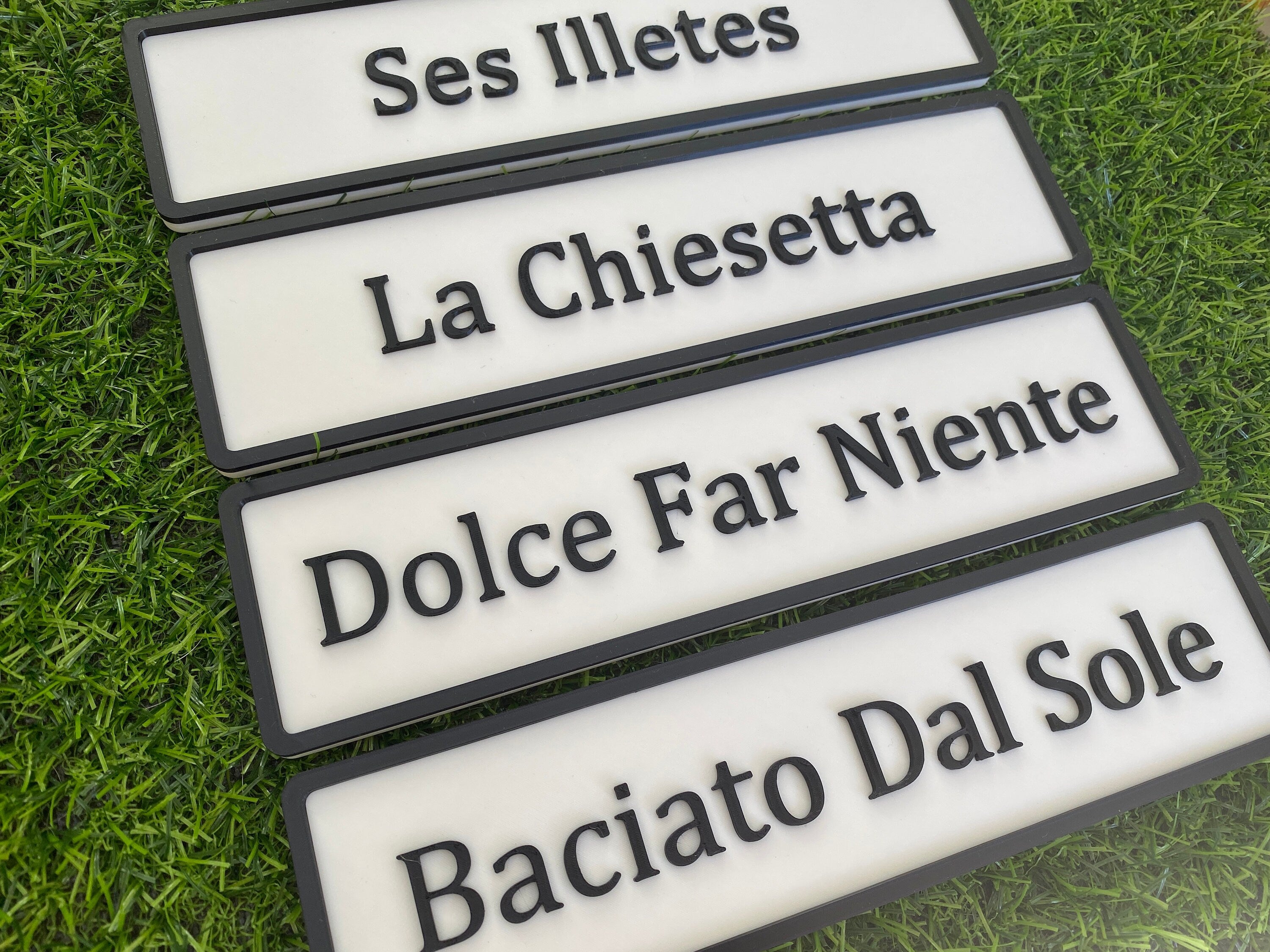 Four white and black contemporary door signs fanned on grass