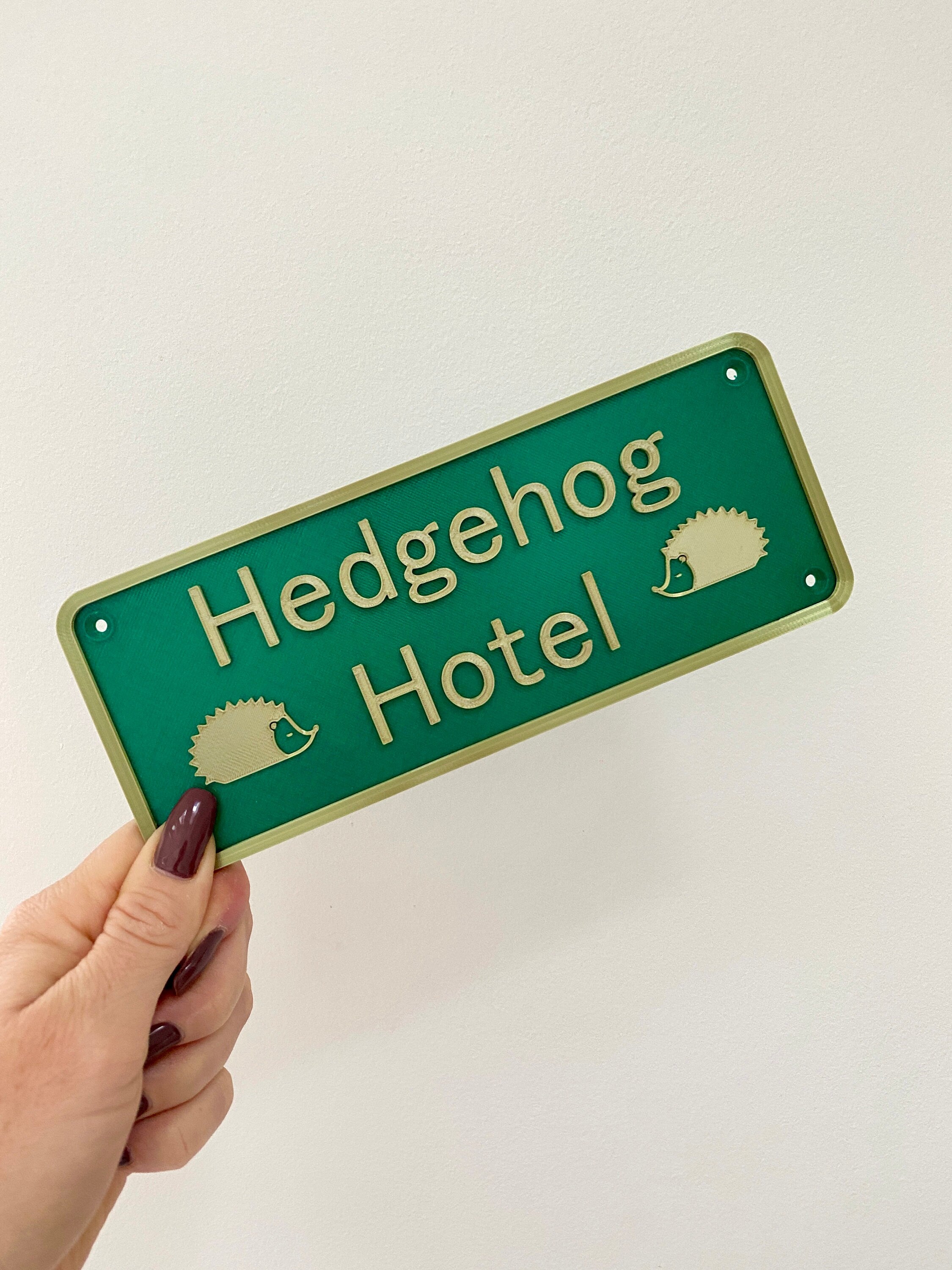 Green and gold Hedgehog Hotel sign held in hand
