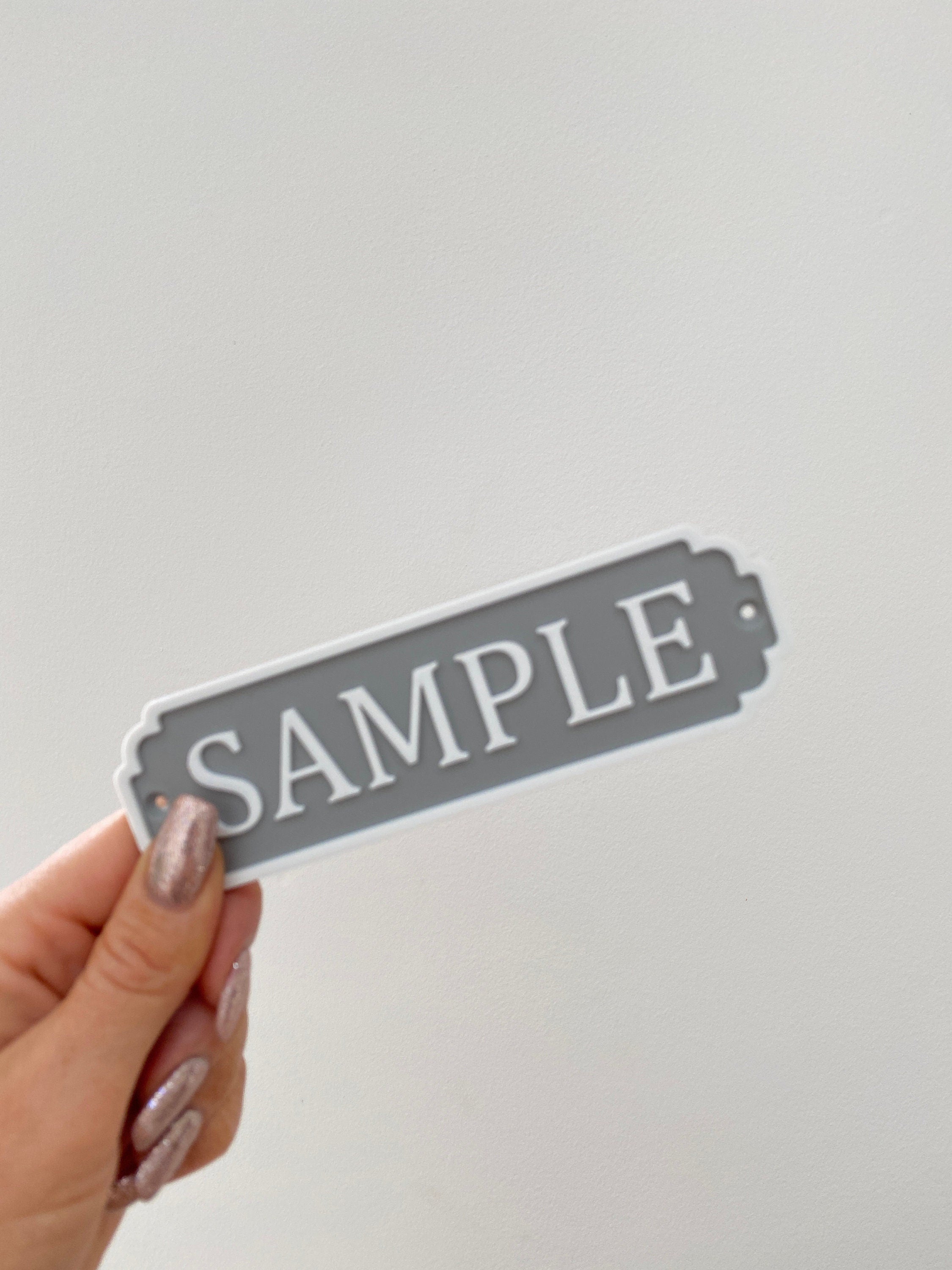 Grey sample classic door sign held in hand