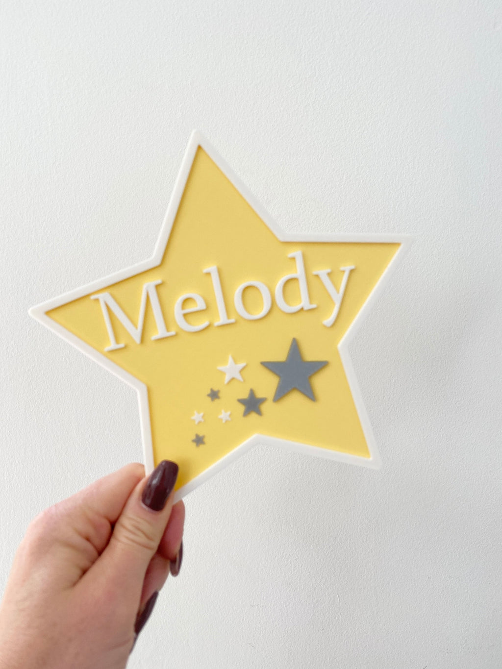 Yellow star bedroom door sign with the name Melody held in hand