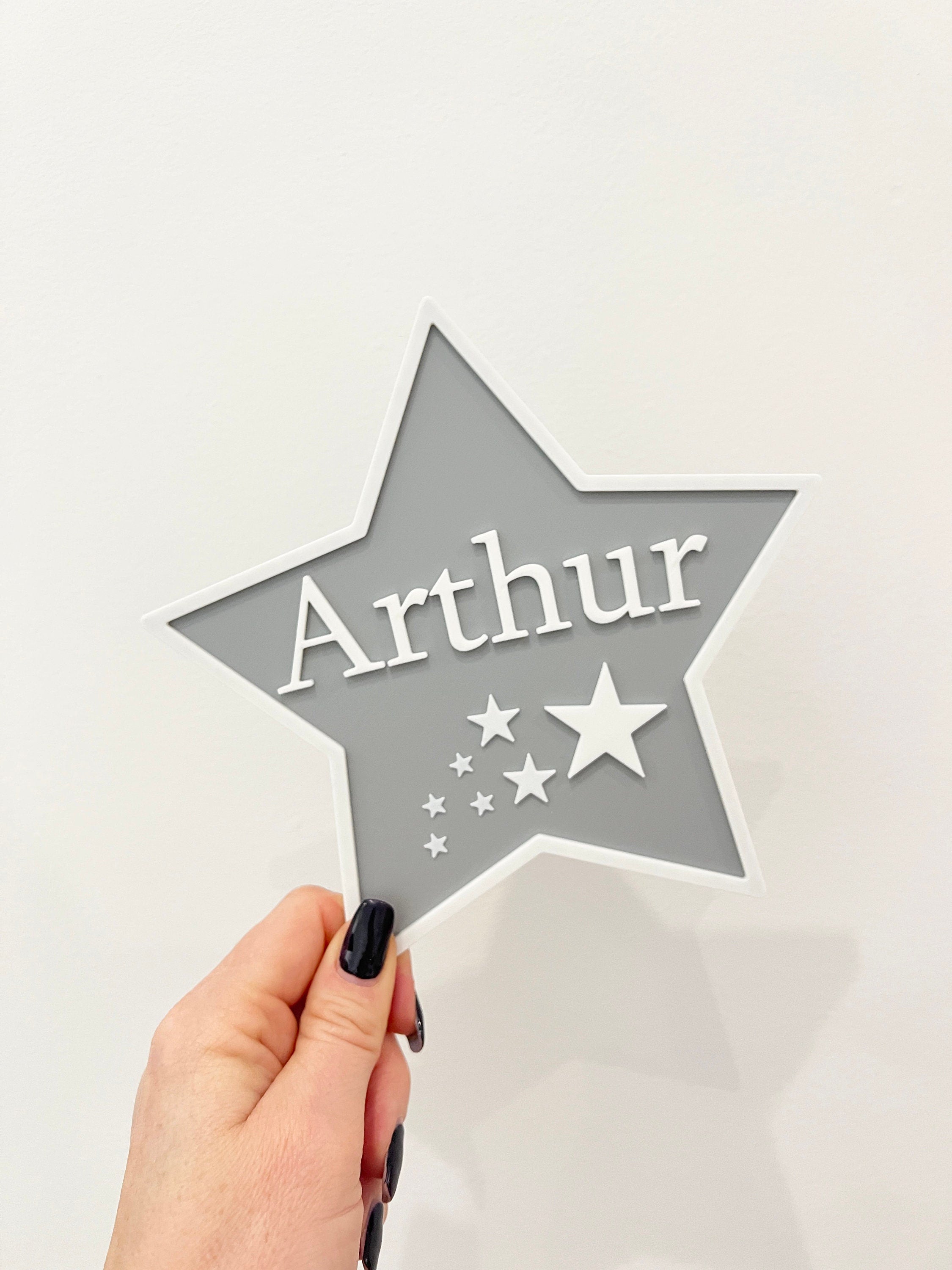 Grey star door sign with the name Arthur held in hand