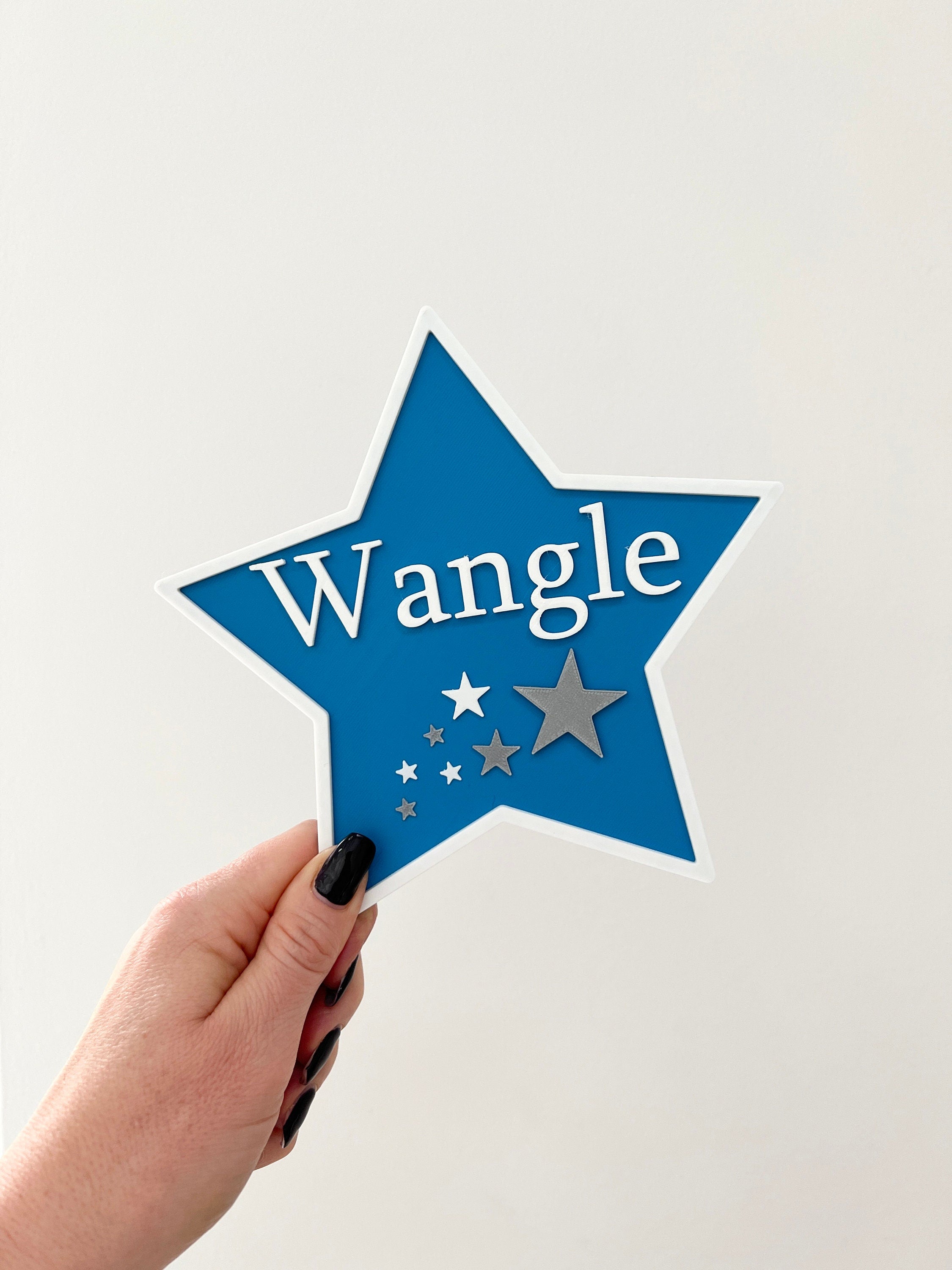 Blue star door sign with the name Wangle held in hand