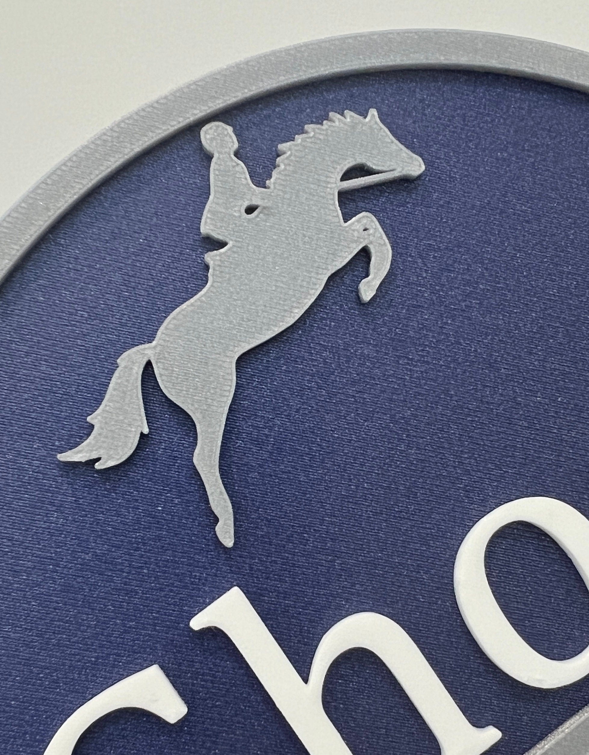 Close-up of the silver rearing horse motif on a navy double motif sign