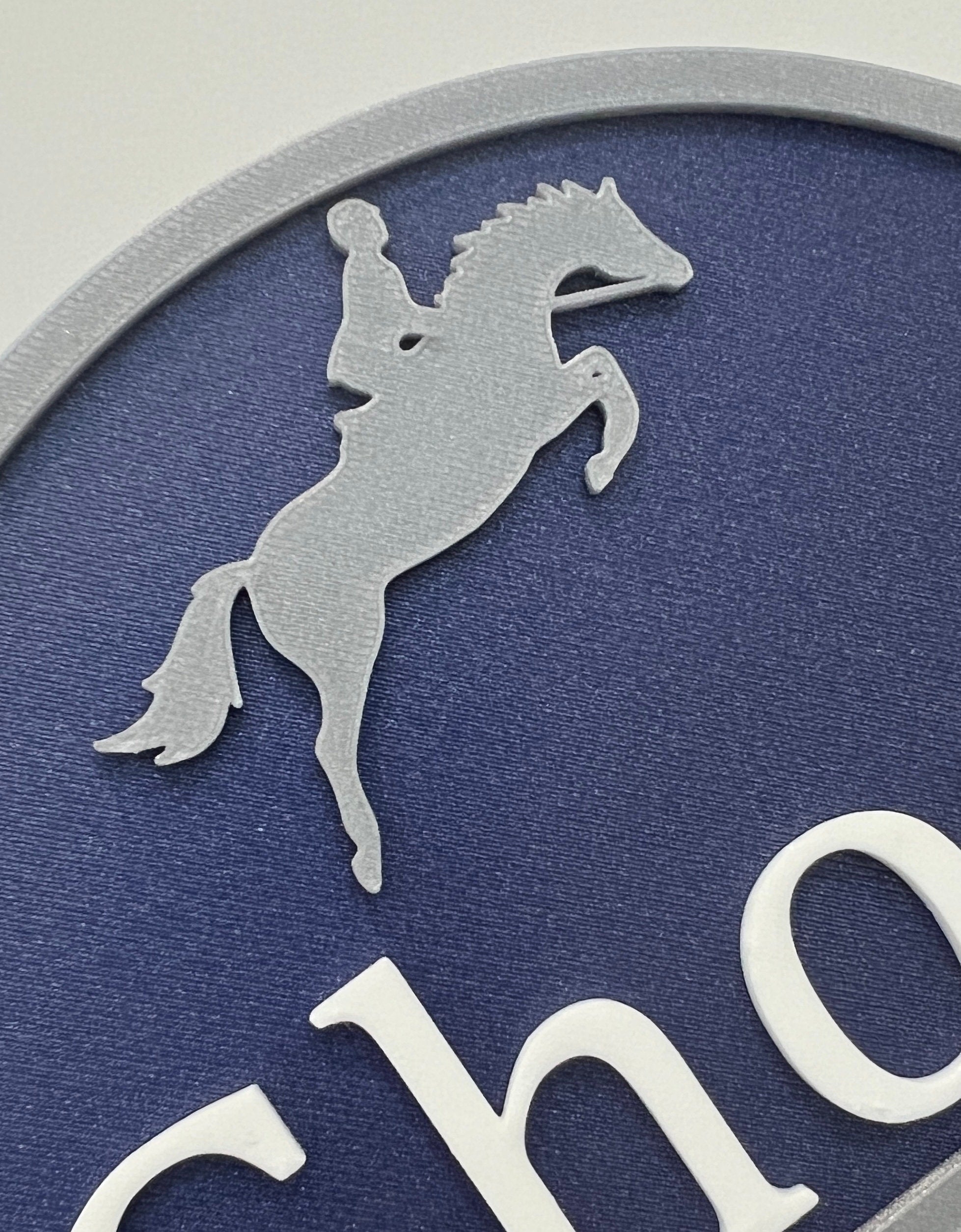 Close-up of the silver rearing horse motif on a navy double motif sign
