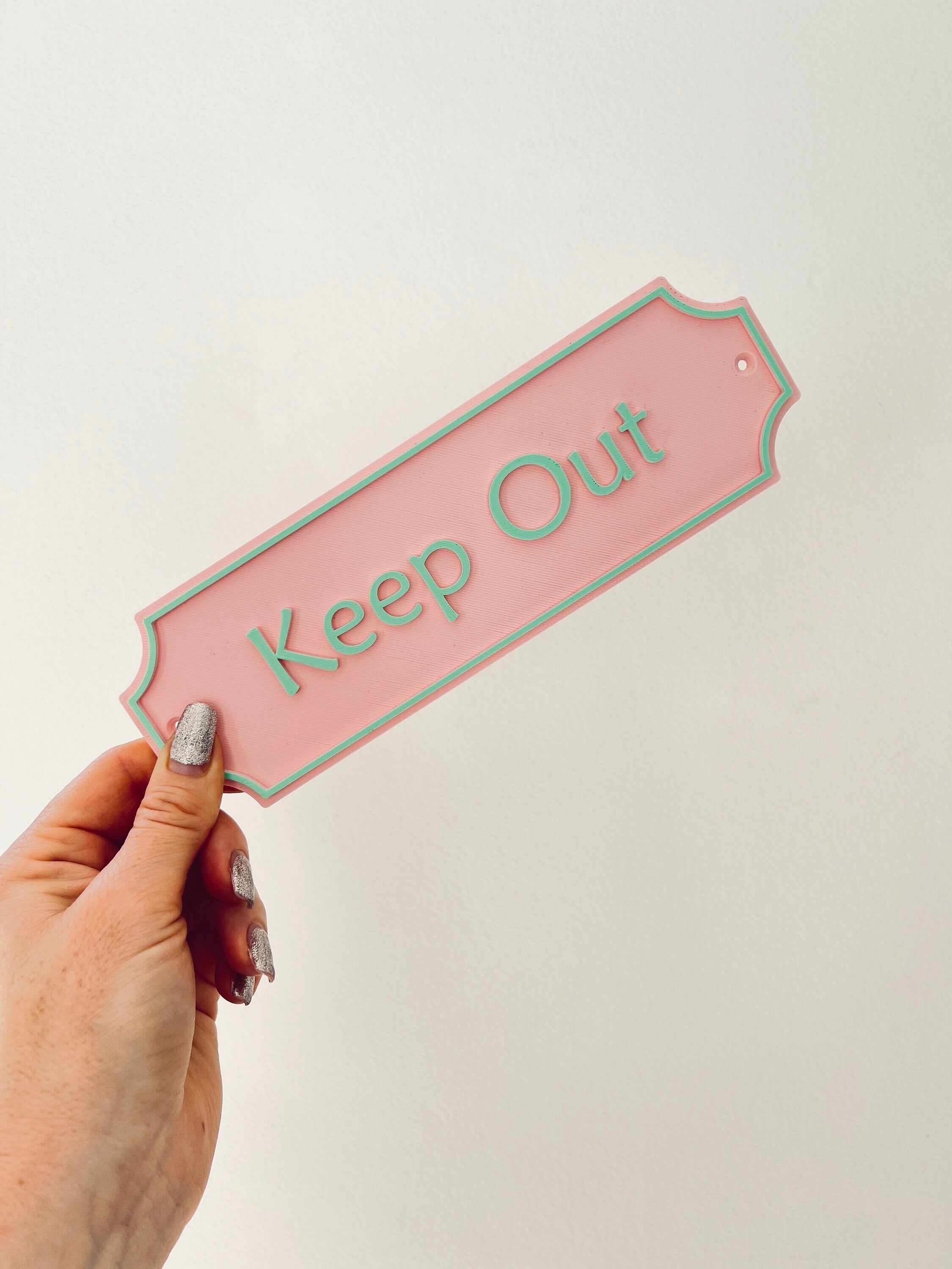 Pastel pink Keep Out Emley sign held in hand