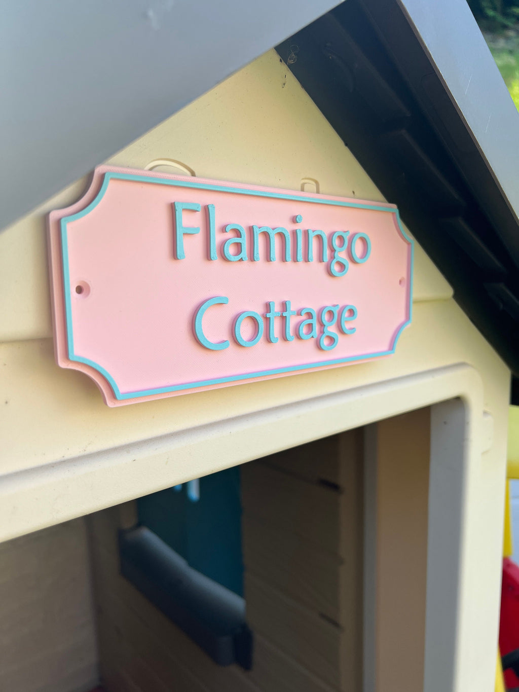 Close-up of the pastel pink Flamingo Cottage playhouse sign