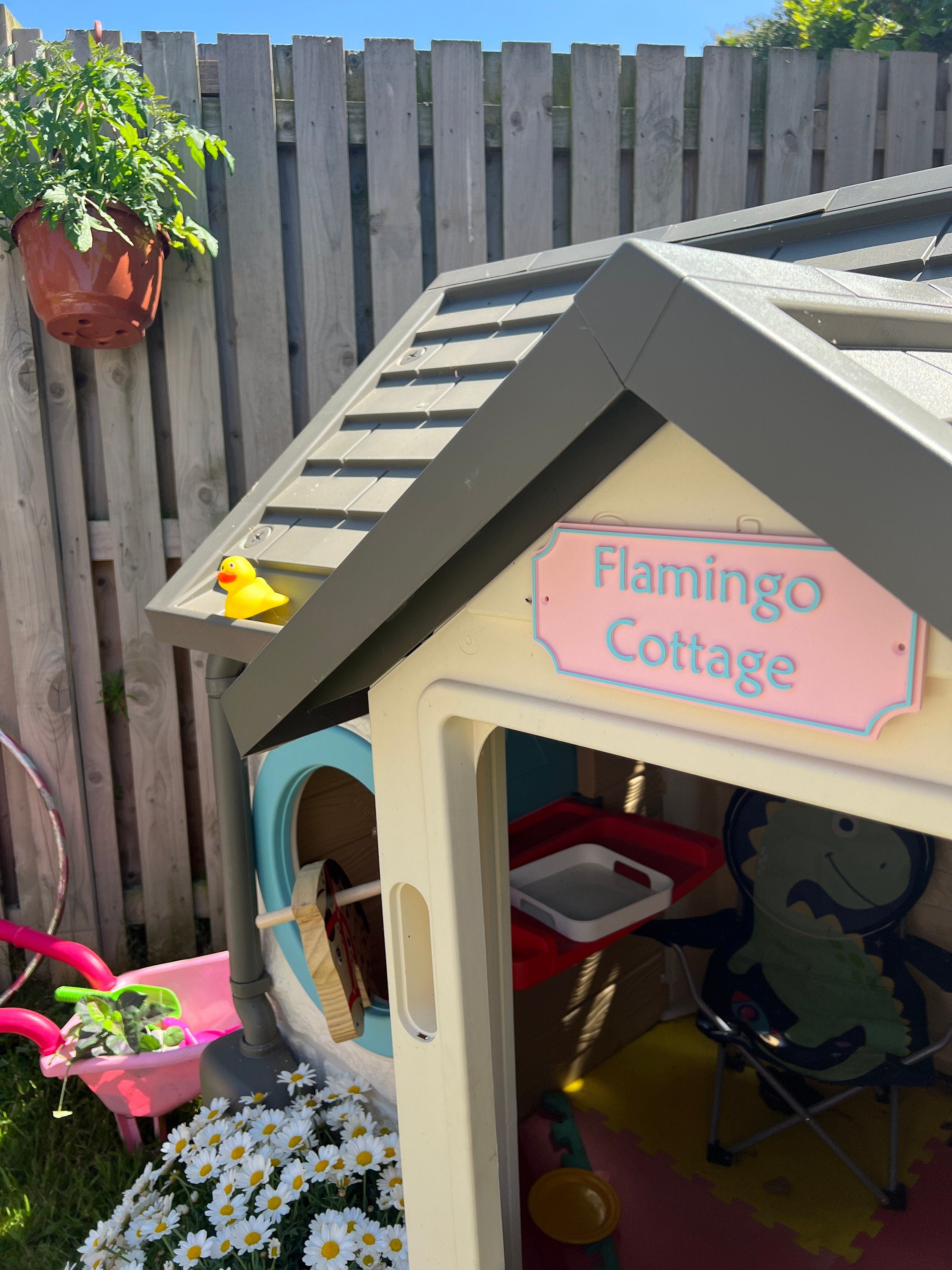 Pastel pink Flamingo Cottage sign on a garden playhouse